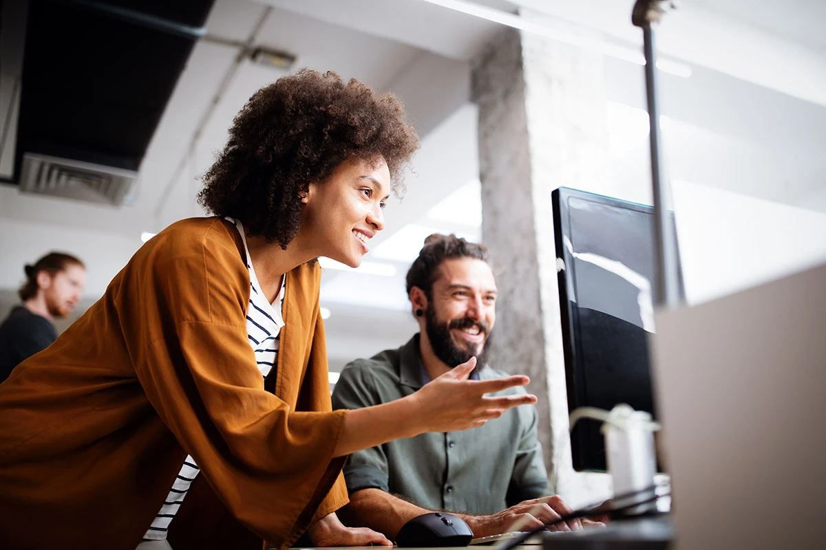 Arbeitskolleg:innen besprehen sich an einem PC-Monitor