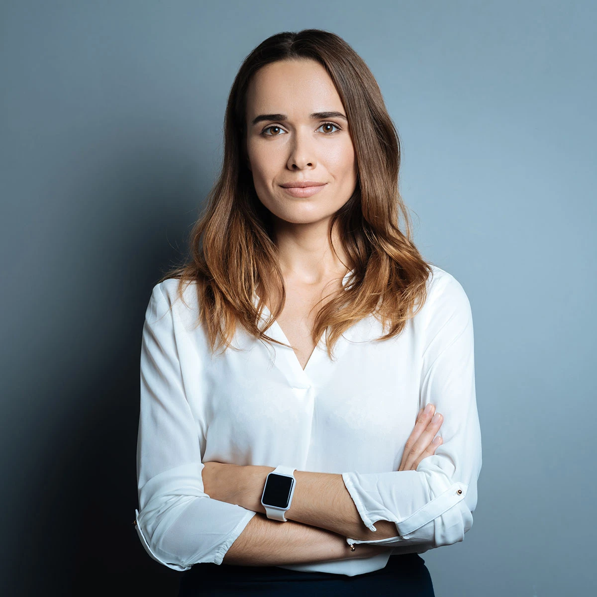 Gesch&auml;ftsf&uuml;hrerin steht mit verschr&auml;nkten Armen vor einer grauen Wand