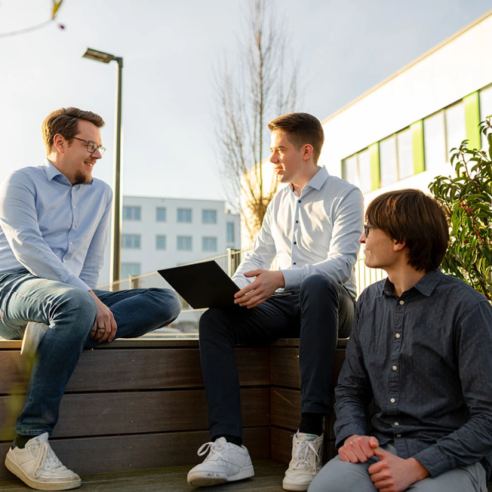 R.iT Teammitglieder in einer Besprechung auf der Firmenterrasse