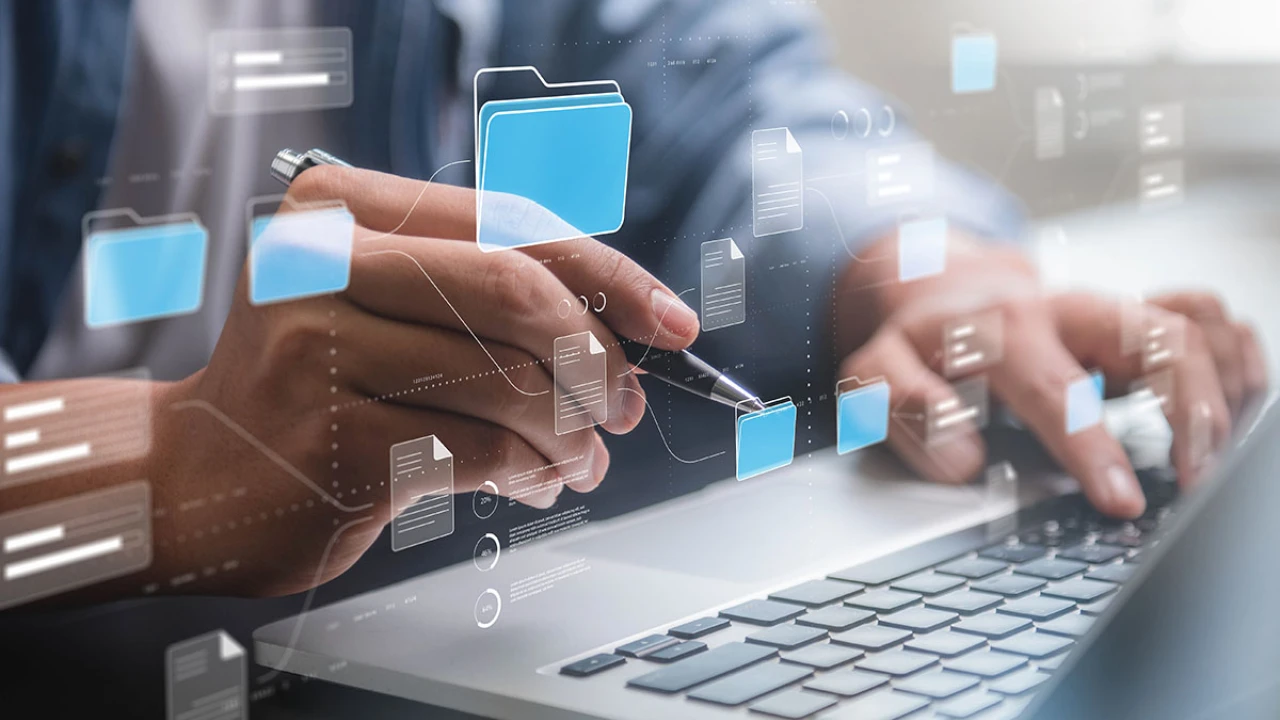 Mann im Business Outfit arbeitet an grauen Laptop und über diesem erscheinen viele Daten Icons