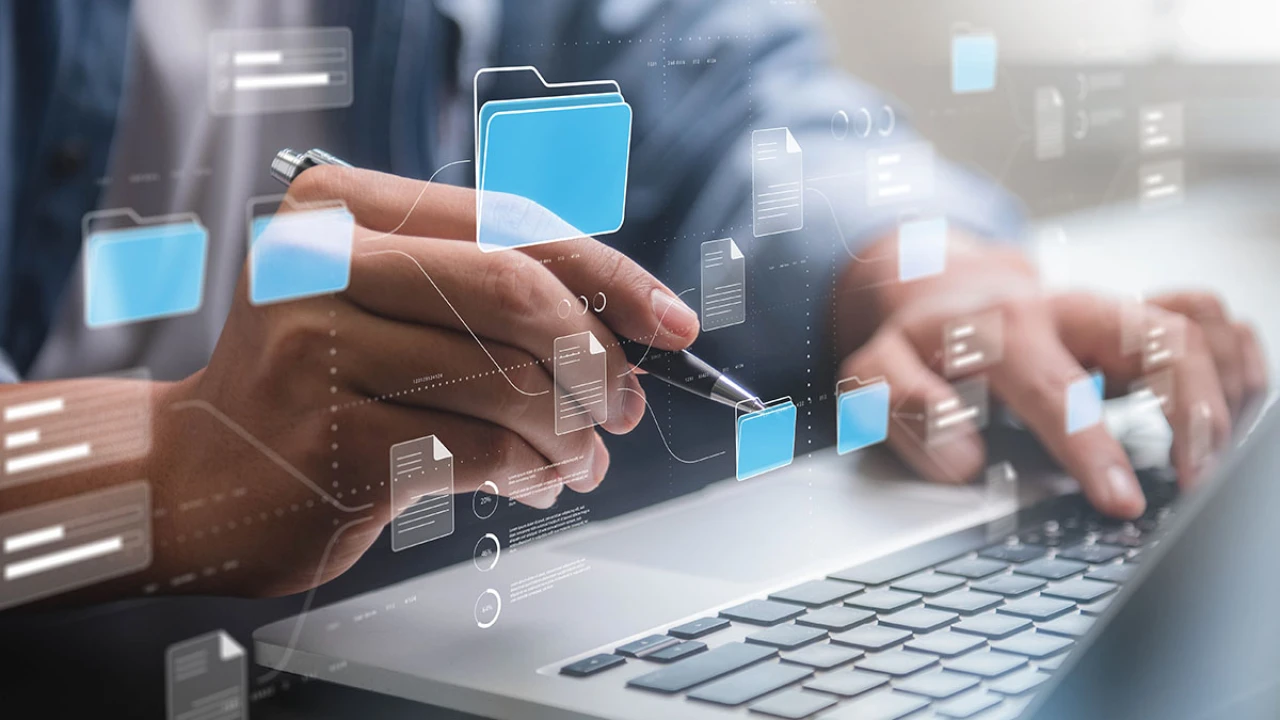 Mann im Business Outfit arbeitet an grauen Laptop und &uuml;ber diesem erscheinen viele Daten Icons